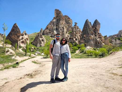 Couple standing among the cave dwellings of the Uchisar valley in Cappadocia, Turkey